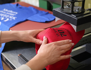 young woman printing on cap at workshop